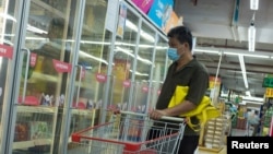 一名男子戴口罩在超市选购冷冻食品。(2020年8月13日)