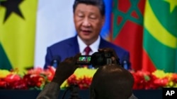 资料照片:2024年9月5日,一名非洲记者在新闻中心拍摄中国国家主席习近平在北京人民大会堂发表中非论坛开幕式致辞的屏幕。