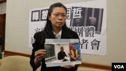 李明哲的妻子李净瑜向媒体展示李明哲以往活动的照片(美国之音杨明拍摄)