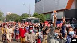 缅甸抗议民众走在仰光街头,并高举象征抗议独裁的三个手指的手势。