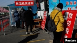 北京市民在进入一个市场前用手机刷健康码。(2021年1月11日)