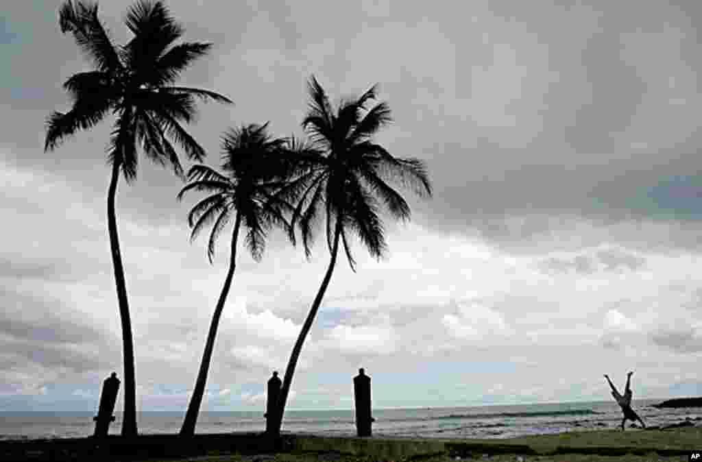 圣多美和普林西比海滩上的棕榈树旁,有人玩倒立。