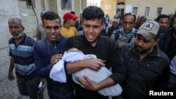 一名男子抱着巴勒斯坦婴儿艾哈迈德·埃尔希姆的尸体,医务人员称他在加沙城的以色列袭击中丧生。