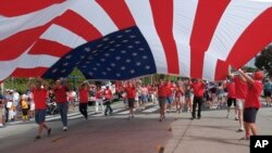 加州圣莫妮卡今年7月4日的游行中参与者手举美国国旗