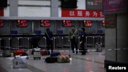 Cảnh sát Trung Quốc đứng cạnh các hành lý còn lại tại phòng vé ở nhà ga sau vụ tấn công đẫm máu, ngày 2/3/2014.