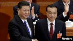 中国总理李克强在北京人大会堂召开的全国人大会议上获连任后与中国国家主席习近平握手。(2018年3月18日)