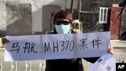 一名马航MH370航班乘客家属手拿标语。(美联社2023年11月27日)