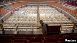 一名身穿防护服的工人正在给一个由体育馆改建的方舱医院消毒,为关舱做准备。(2020年3月8日)