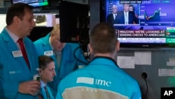 2020年3月17日,纽约证券交易所交易员在听特朗普总统在白宫的电视新闻发布会。